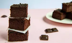 Ciemne, wilgotne brownie z fasoli, ułożone w stosik, obok kawałków czekolady.
