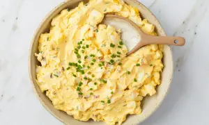 Kremowa pasta jajeczna z jogurtem, posypana szczypiorkiem, w ceramicznej misce. Idealna na kanapki.