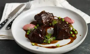 Pyszne policzki wołowe w sosie, podane z groszkiem i różowym purée. Idealny przepis na wykwintny obiad.