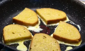 Pięć kromek chleba w jajku smaży się na patelni, tworząc pyszne śniadanie.