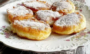 Puszyste racuchy na jogurcie, posypane cukrem pudrem, kuszą swoim złotym kolorem i delikatnością. Idealne na deser!