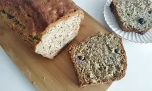Domowy chlebek bananowy z kawałkami orzechów i rodzynek, pokrojony na desce.