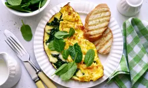 Pyszny omlet ze szpinakiem, podany z grzankami i świeżymi liśćmi szpinaku. Idealny na zdrowe śniadanie.