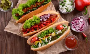Trzy apetyczne hot dogi z sałatą, pomidorami, ogórkiem, cebulą i papryką. Idealne na letnie grillowanie!
