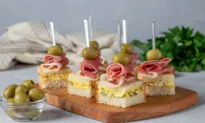 Eleganckie mini przekąski na imprezę: kanapki z jajeczną pastą, szynką parmeńską i oliwką na wykałaczce.