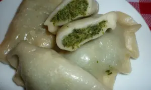Pyszne pierogi ze szpinakiem i mozzarellą, jeden przekrojony, ukazujący zielone nadzienie.