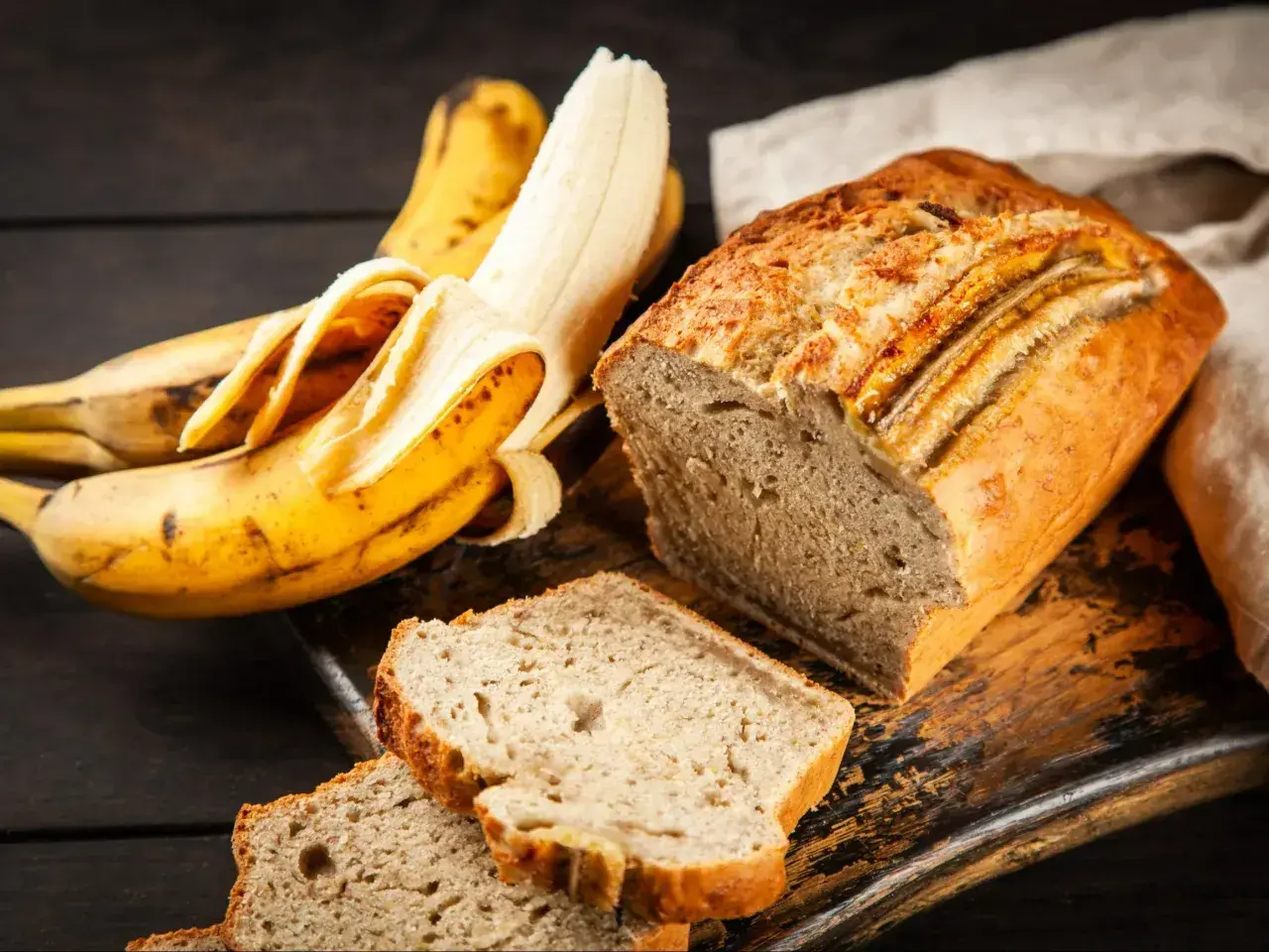 Pyszne ciasto z bananami, obok leżą dojrzałe banany. Idealne na deser lub śniadanie.