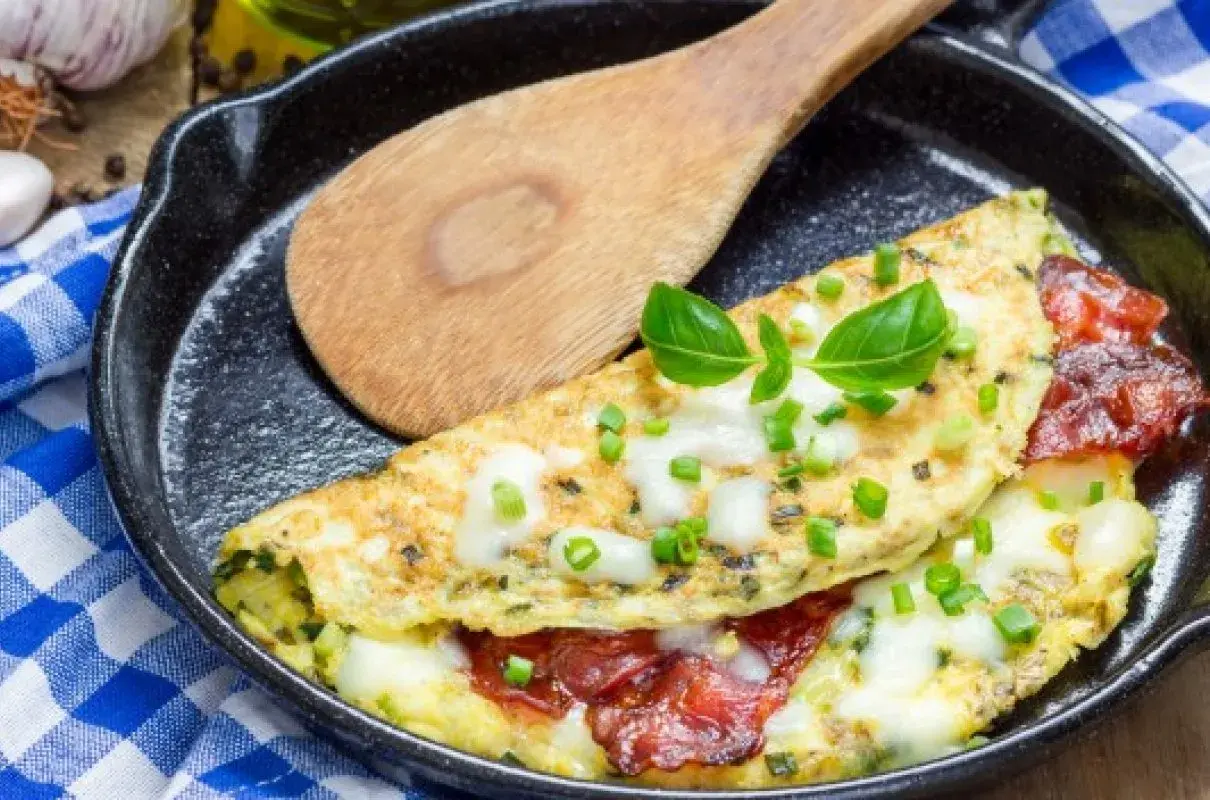 Pyszny omlet z serem, pomidorami i szczypiorkiem na patelni. Idealny omlet przepis na śniadanie.