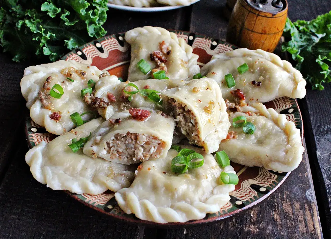 Pyszne pierogi z kaszą gryczaną i twarogiem, posypane szczypiorkiem i skwarkami.
