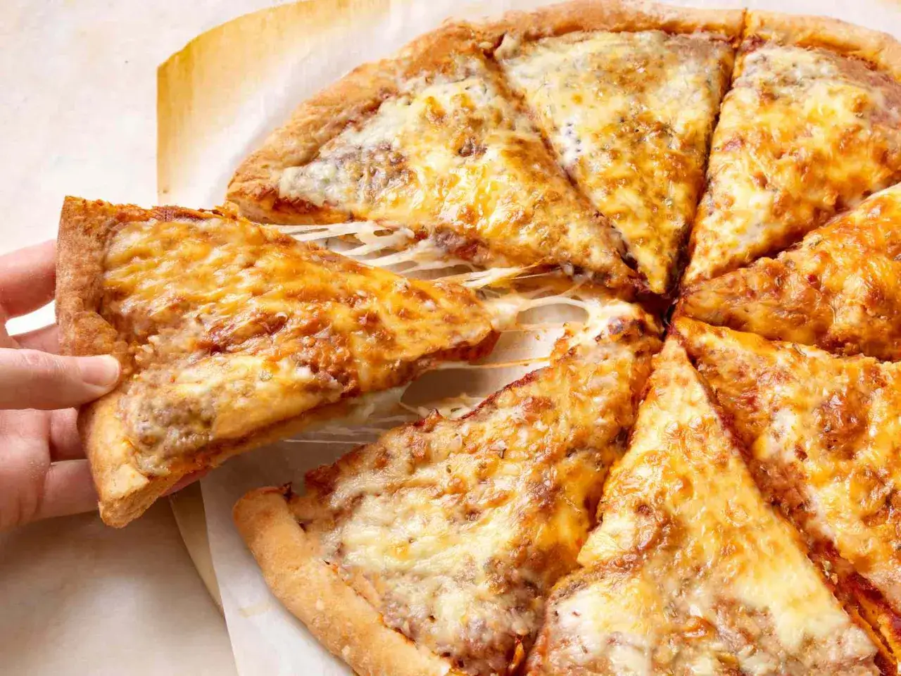 Ręka podnosi kawałek pysznego, ciągnącego się sera z pizzy. Idealne ciasto na pizzę z chrupiącymi brzegami.