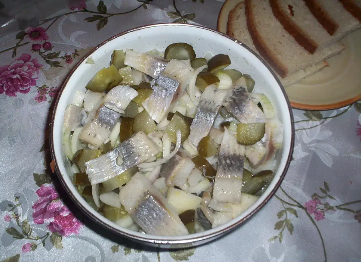 Śledzie w oleju z cebulką i ogórkiem kiszonym, gotowe do podania. Idealny przepis na szybką przekąskę.