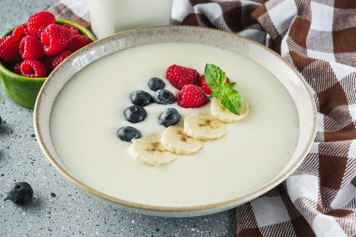 Pyszna kasza manna z malinami, borówkami i bananem, udekorowana miętą. Idealne śniadanie.