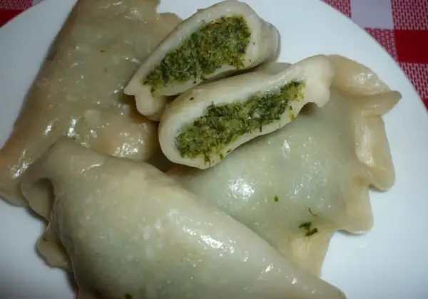 Pyszne pierogi ze szpinakiem i mozzarellą, jeden przekrojony, ukazujący zielone nadzienie.